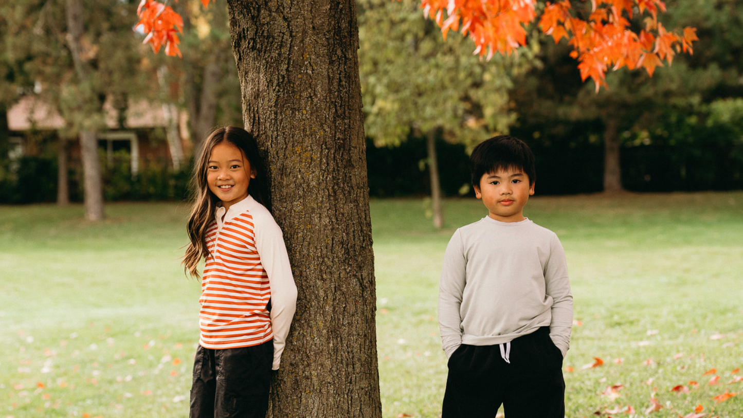 Two children wearing UPF 50+ clothing outdoors, showing everyday sun protection for kids