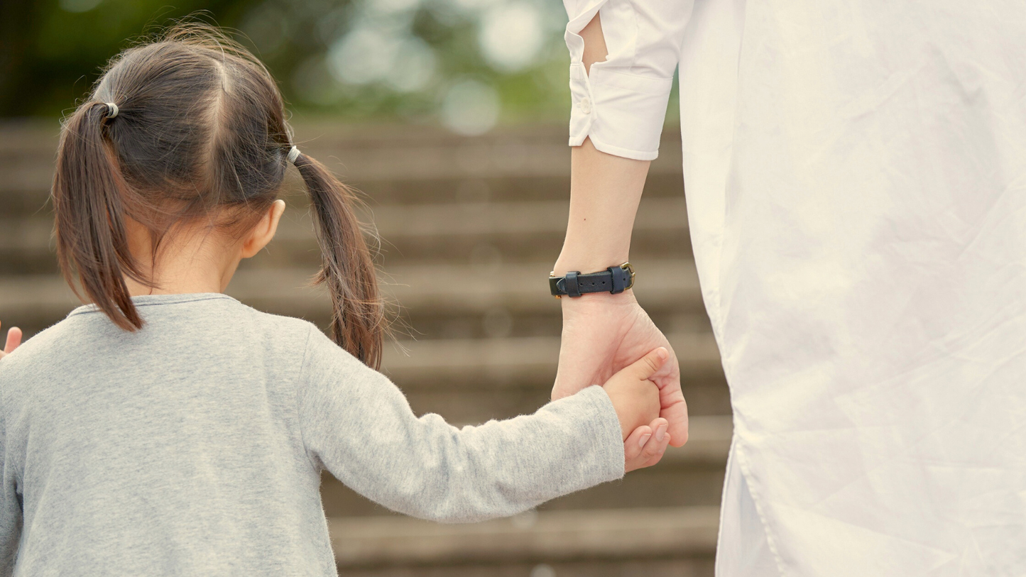 Parent holding a child’s hand while walking outdoors.