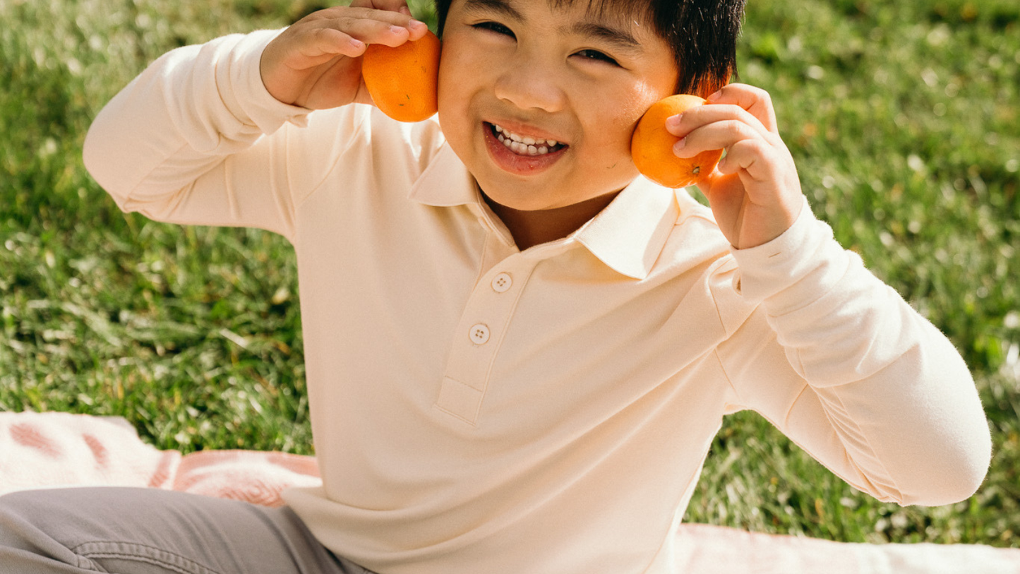 Child wearing an Ember & Ray UPF 50+ sun shirt outdoors on a bright day, showing everyday sun protective clothing for kids